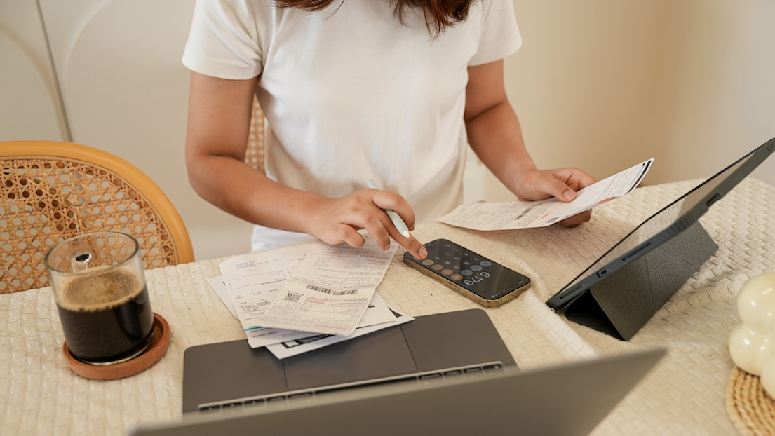 Woman planning budget and using calculator on smartphone