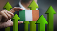 A man in a suit holds a small Irish flag in front of him, surrounded by upward-pointing green arrows that represent successful careers in Ireland
