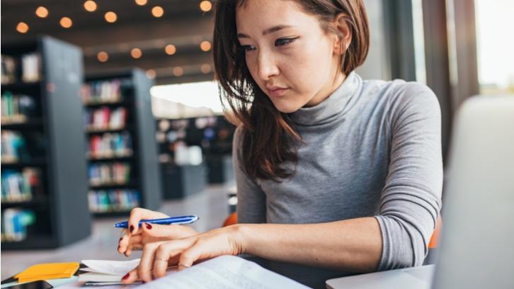 Young woman taking notes in front of a laptop