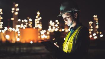 Asian man engineer using digital tablet working late night shift at petroleum oil refinery.
