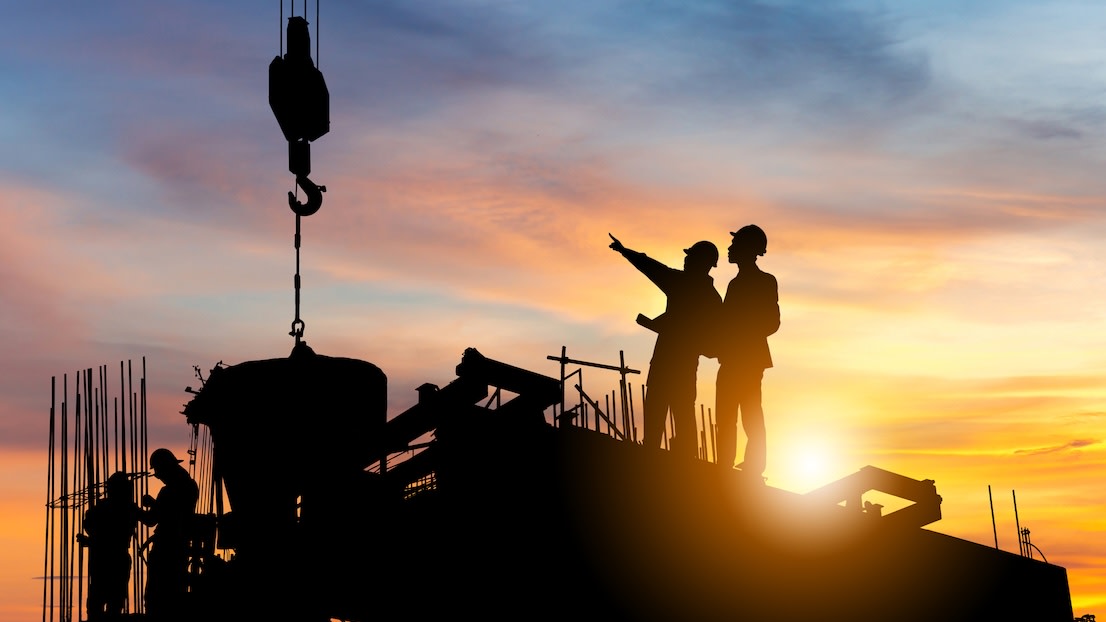 Managers checking project at building site background, construction site at sunset