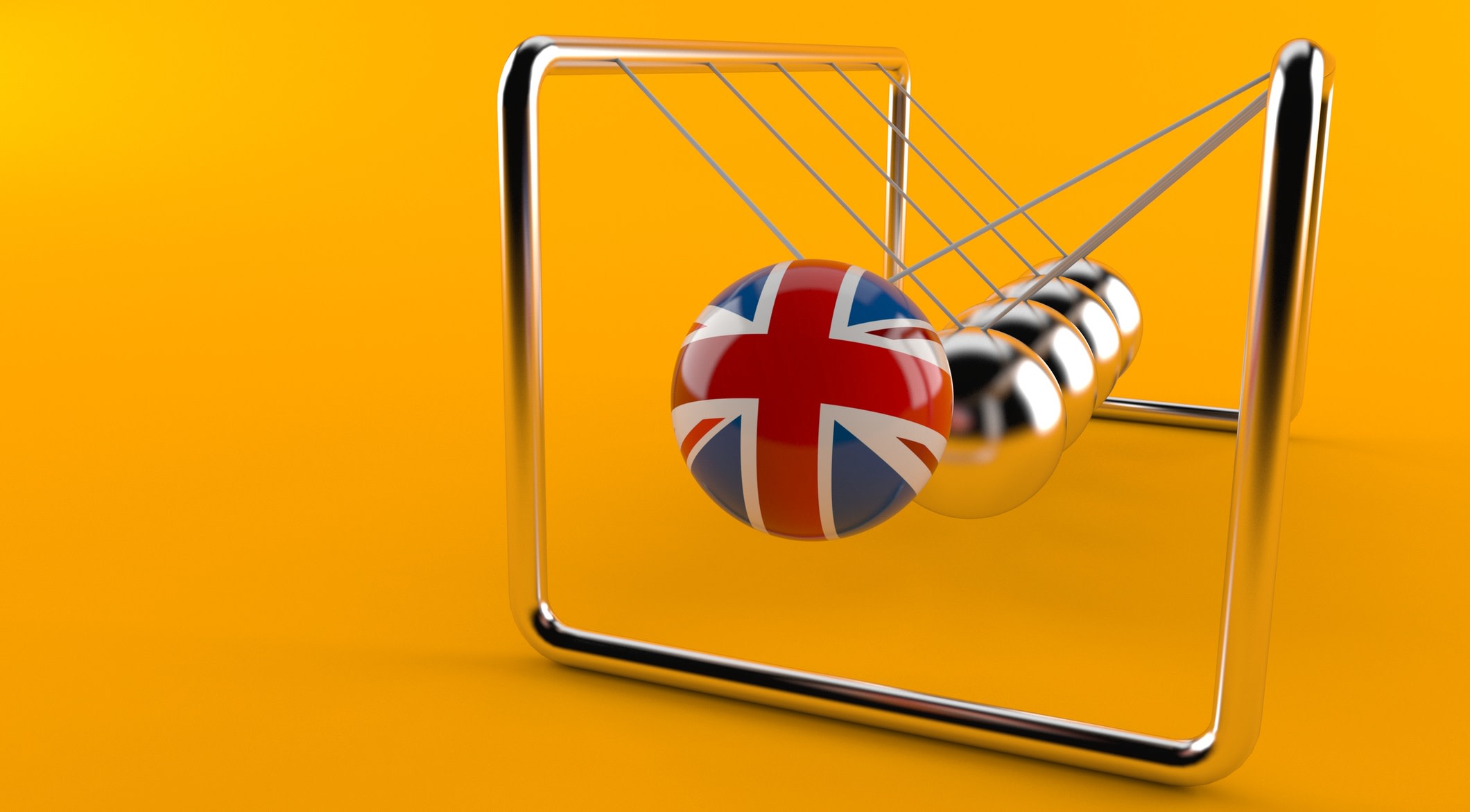A Newton's cradle in which the first ball has a UK flag design. It is about to hit the other balls, which are silver.