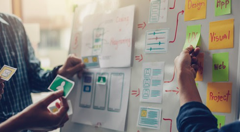 Two web developers using a whiteboard to plan a website.