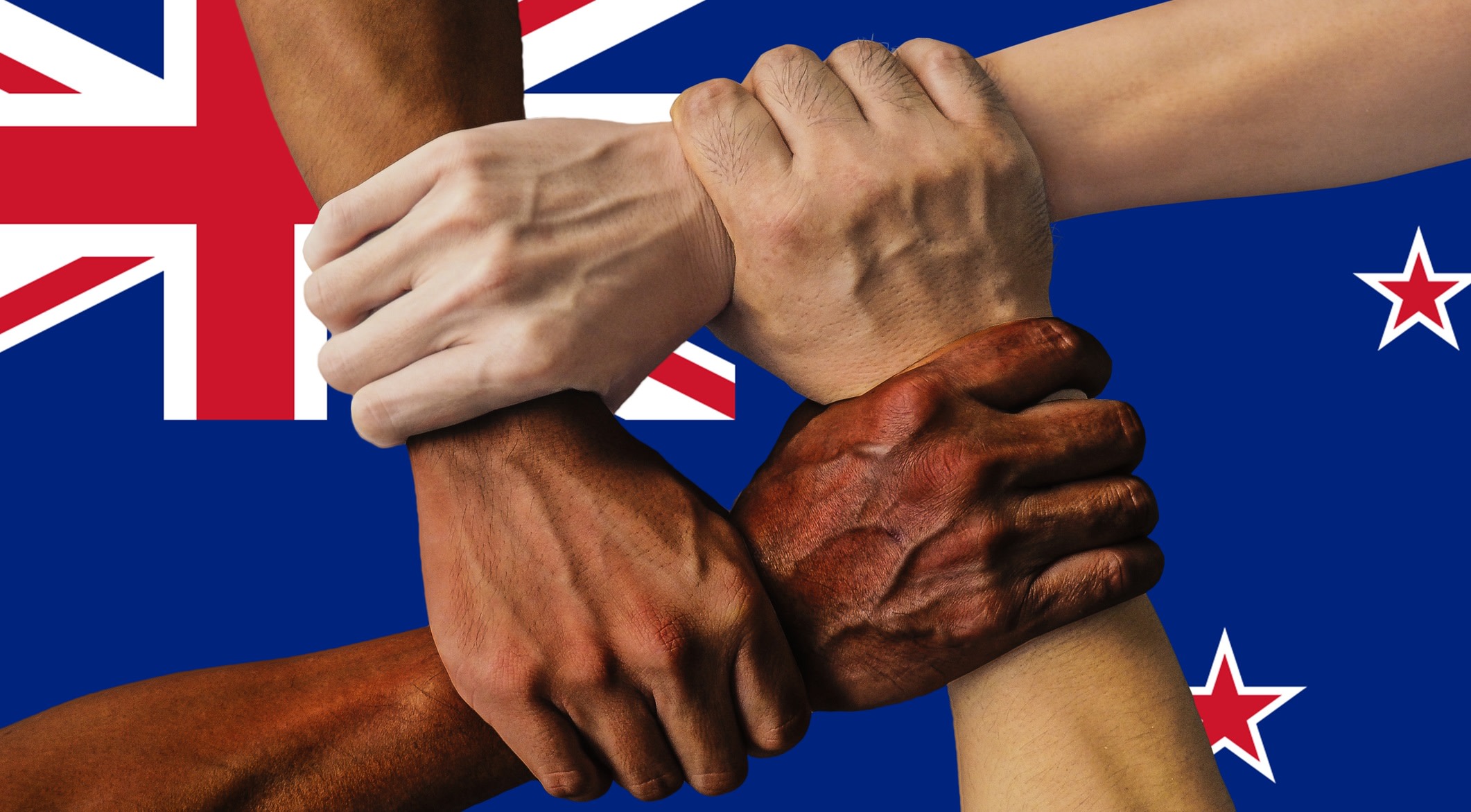 Four hands symbolise strength in unity by clenching each other's accompanying arms to form a square over the flag of New Zealand