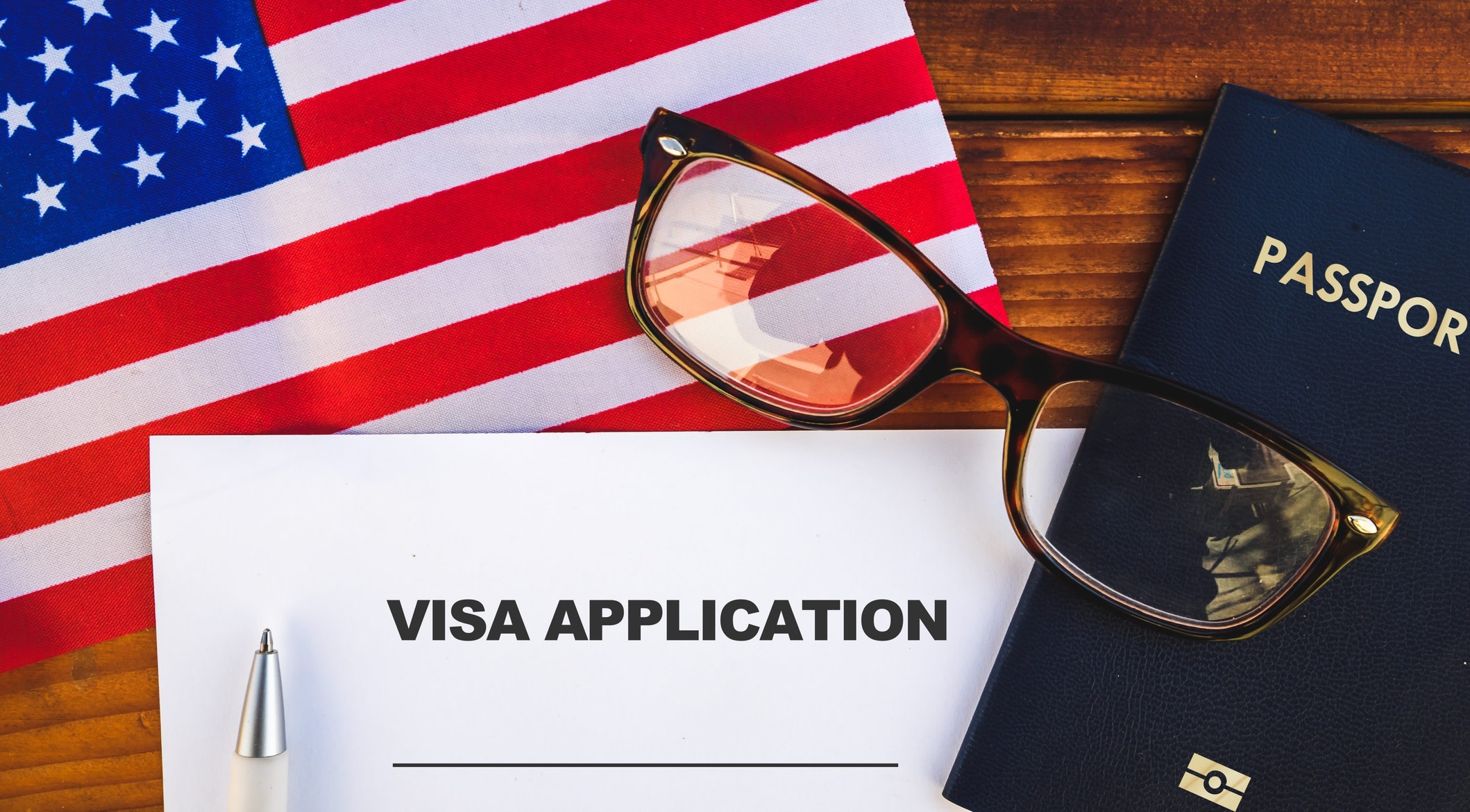 Graphic representing USA visa applications, with a passport and application form resting on an American flag
