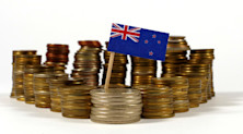Graphic representing funding in New Zealand, with the country's flag emerging over a large pile of coins