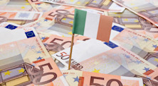 A small Irish flag stands above a pile of 50 Euro notes