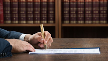 Lawyer writing on legal documents at desk in courtroom