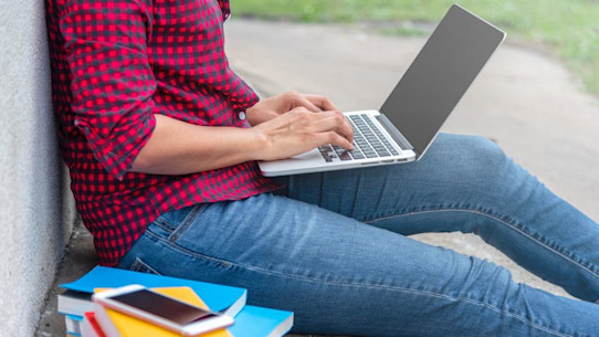 Female university student researching on a laptop outside