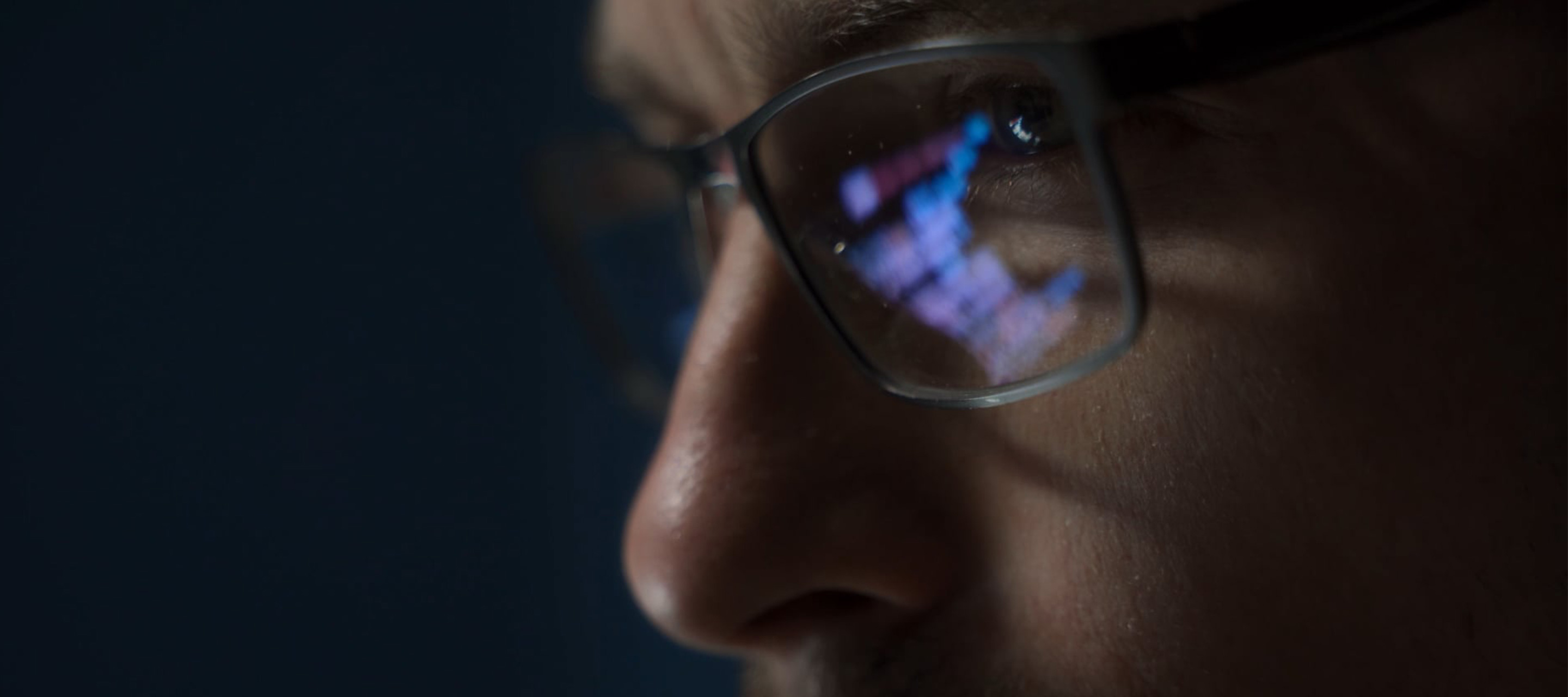 person looking at computer reflected in glasses 