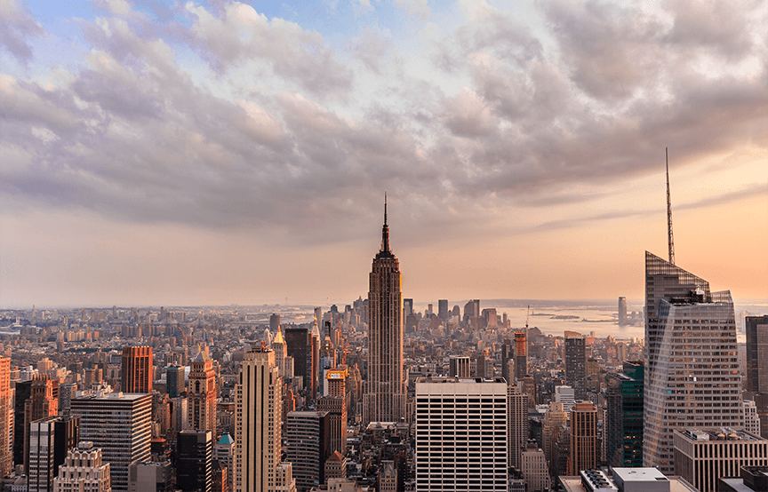 light orange sky with clouds at sunset overlooking city skyline