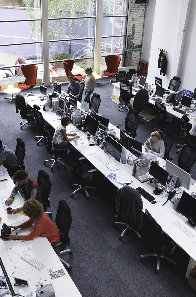 Overheard photo of an open office layout with people working.
