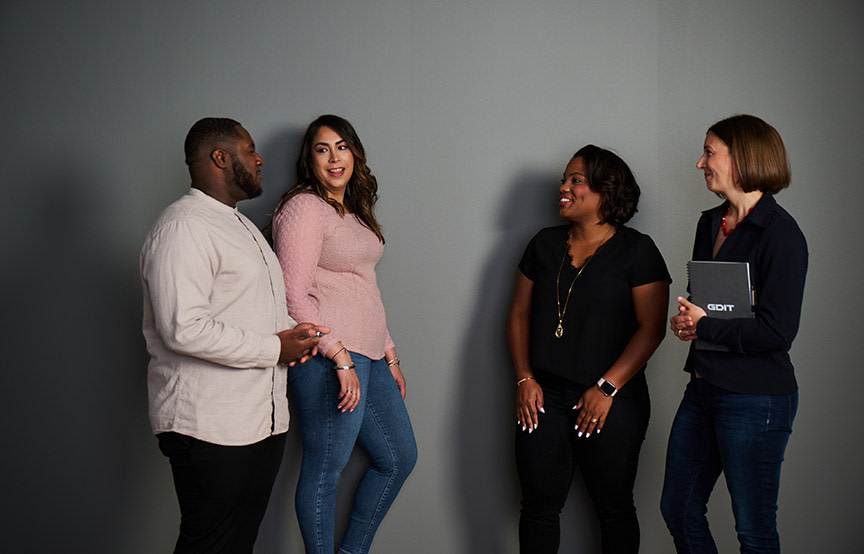 group of diverse colleagues gathered by a grey wall 