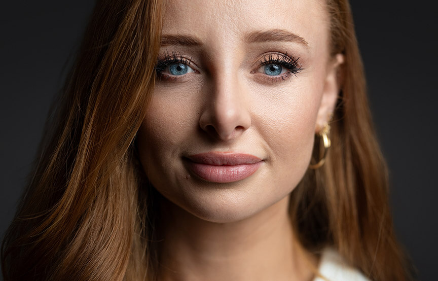 Businesswoman with long red hair and bright blue eyes is giving a subtle smile