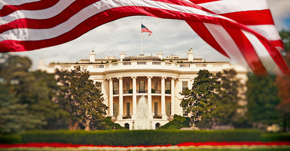 The White House with an American flag being waved above to frame the image