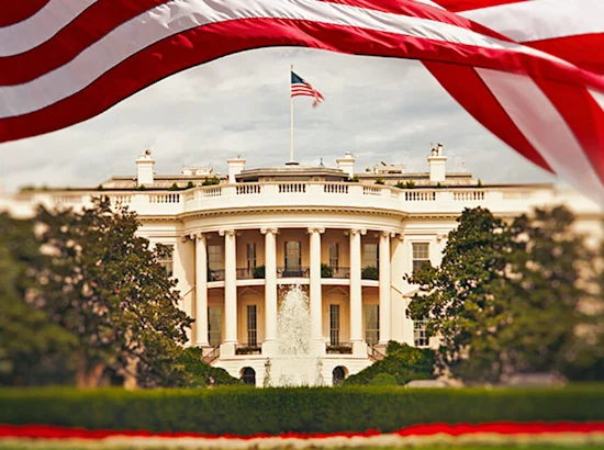 The White House with an American flag being waved above to frame the image