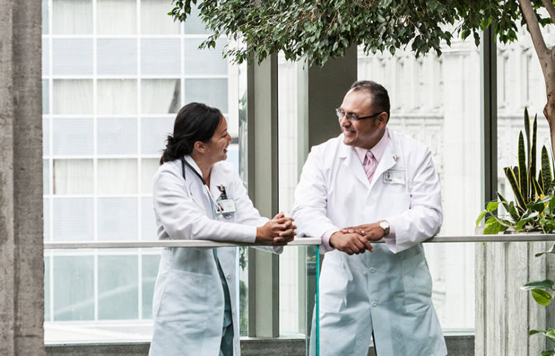 a man and woman in lab coats talking on a balcony