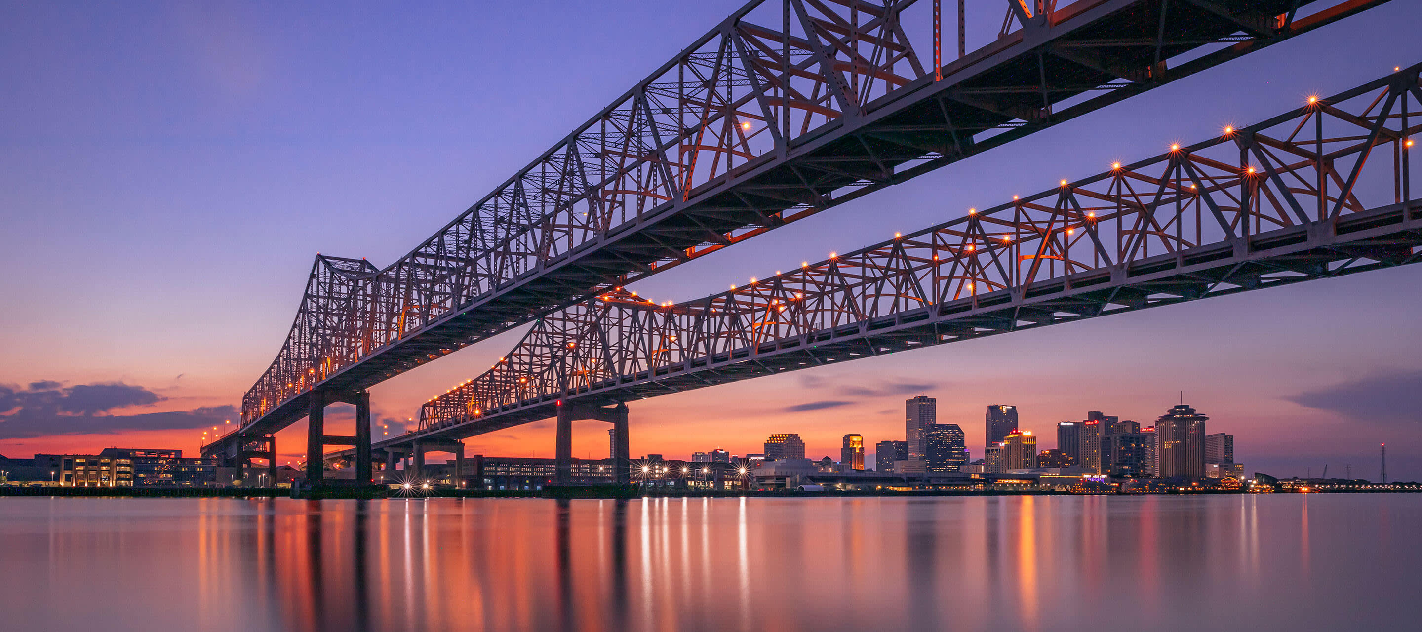 image shows sunset over New Orleans, LA bridge