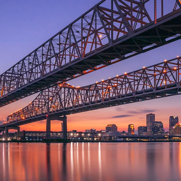 image shows sunset over New Orleans, LA bridge