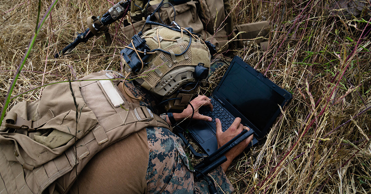 soldier on the ground looking at computer 
