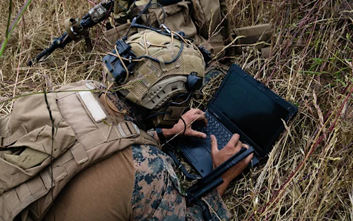 soldier on the ground looking at computer