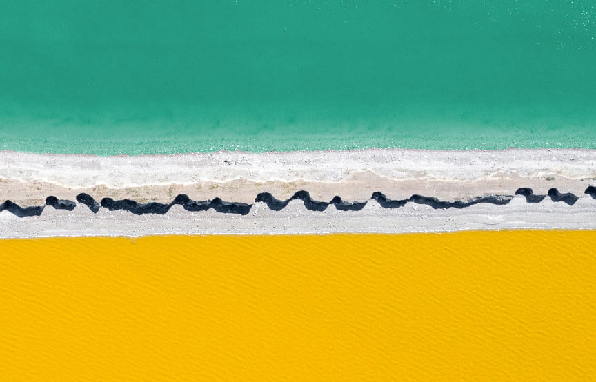 edge of water with yellow sand and blue waters