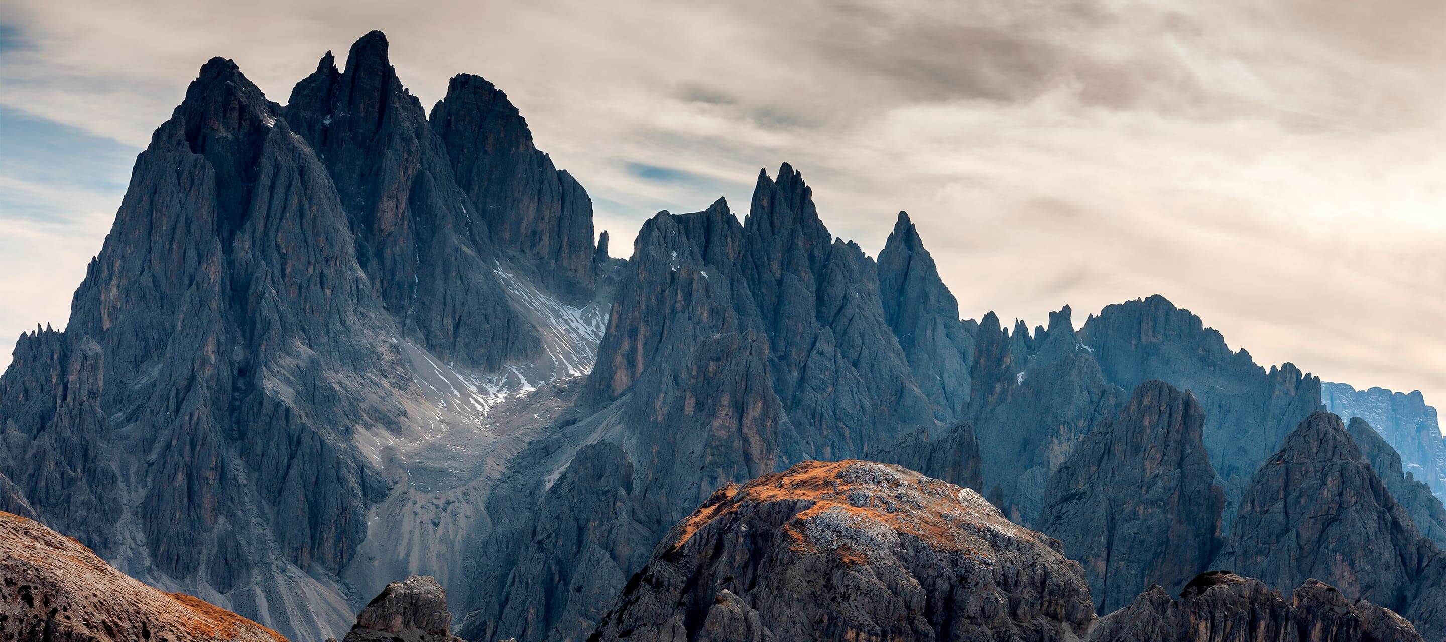 image shows mountains with pointed tops and grey clouded sky