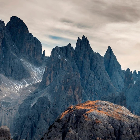image shows mountains with pointed tops and grey clouded sky