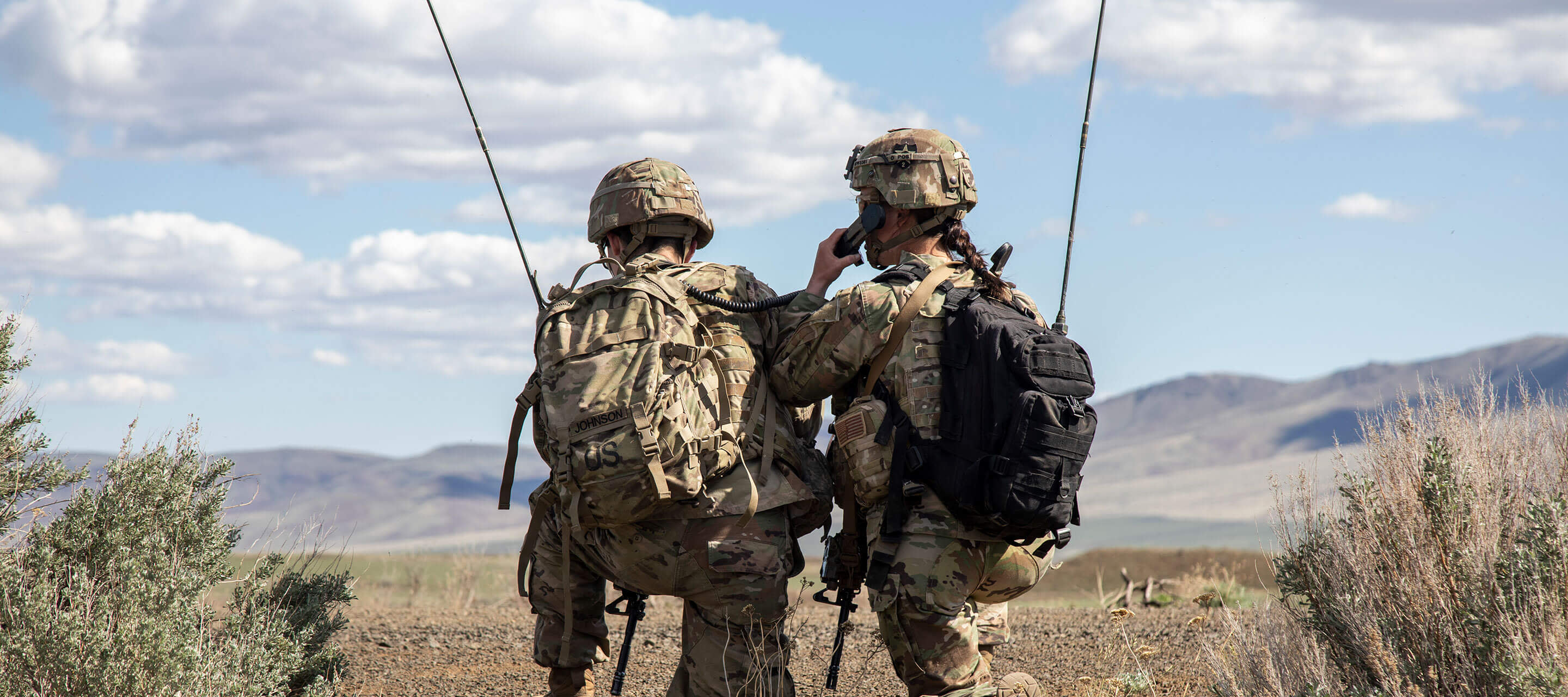 two soldiers kneeling in the field together