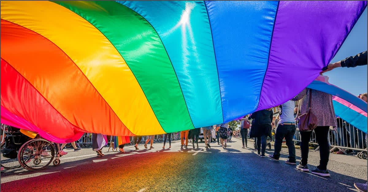 image shows rainbow sheet and legs of people holding it