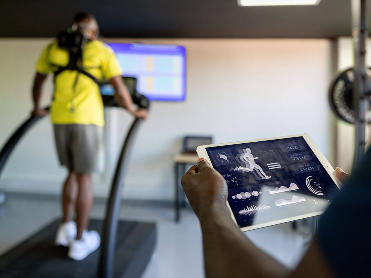 person running on treadmill while someone is looking at a tablet
