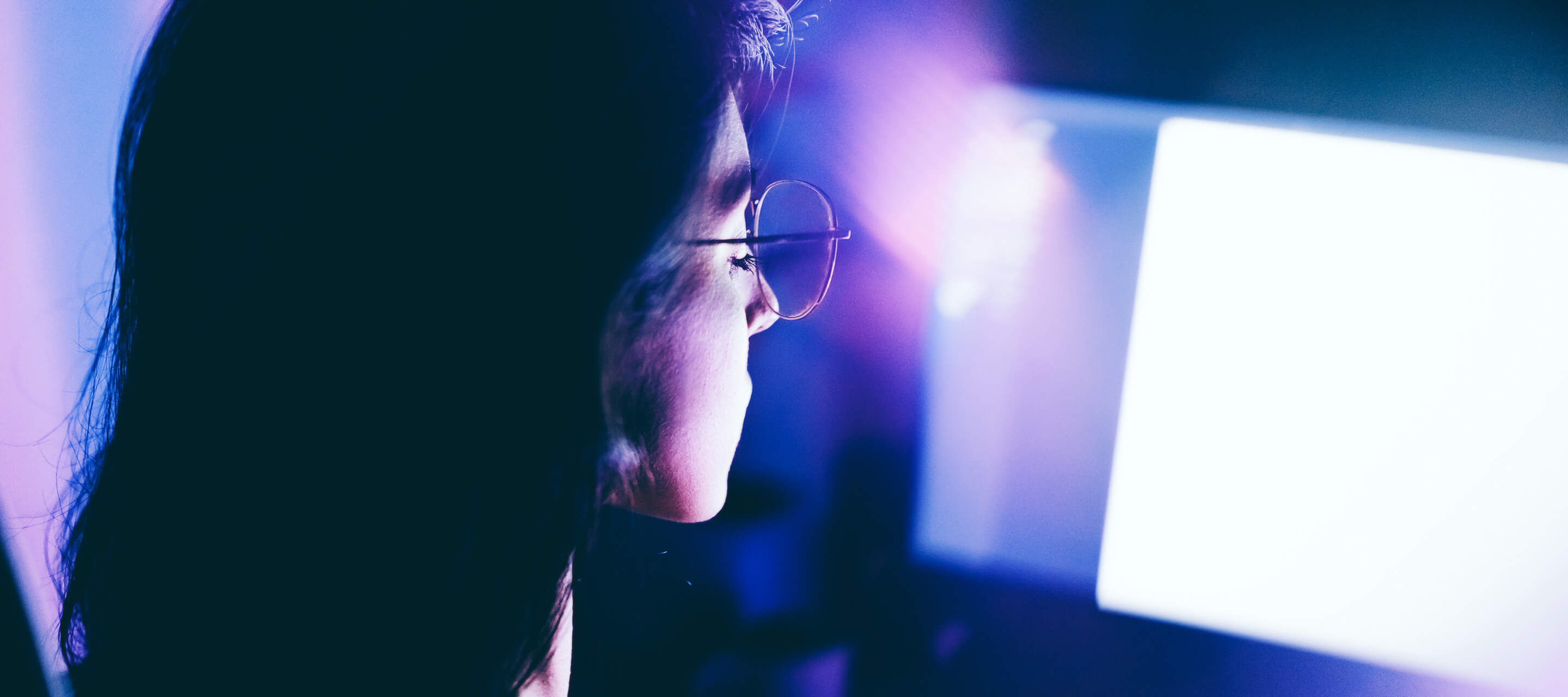 young woman working late on computer in a dimly lit room