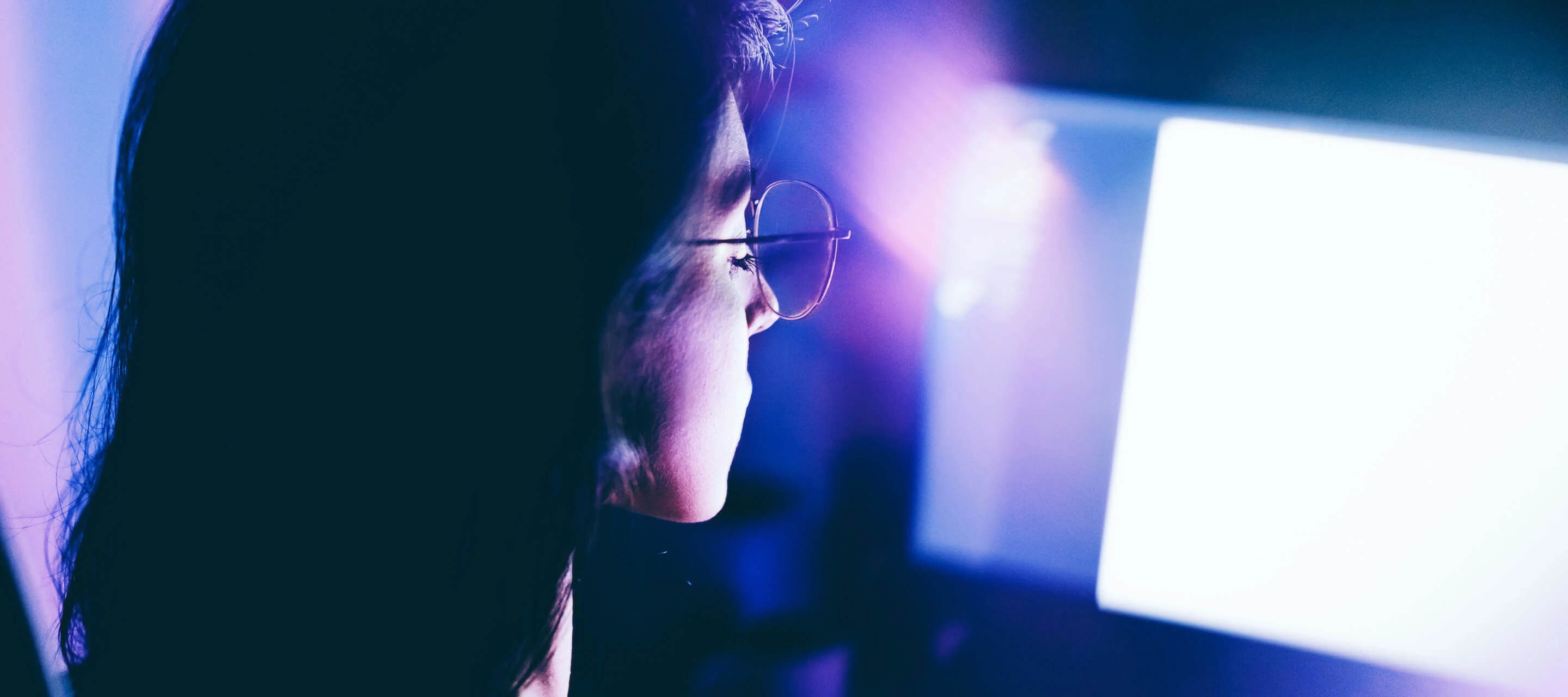 young woman working late on computer in a dimly lit room