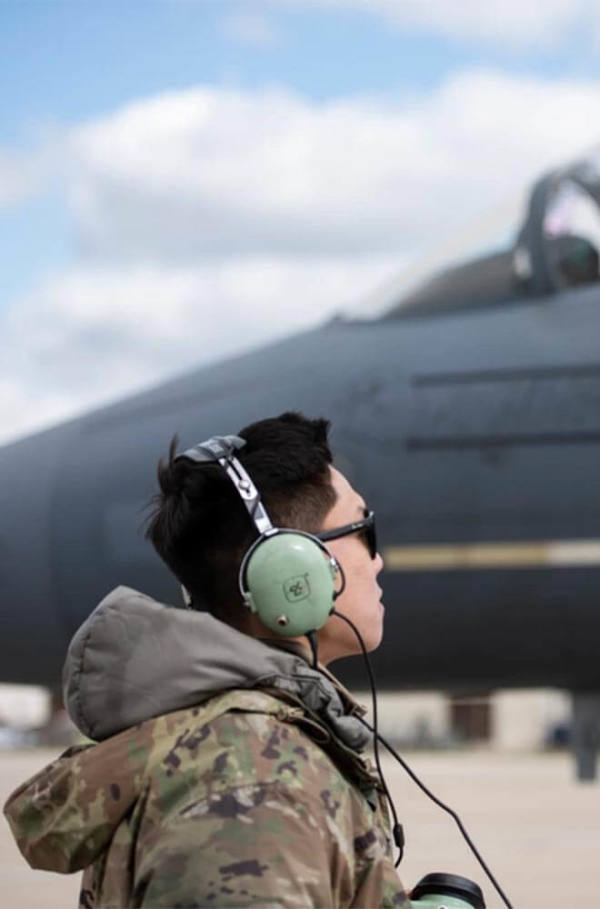 soldier with headphones looking at a plane 