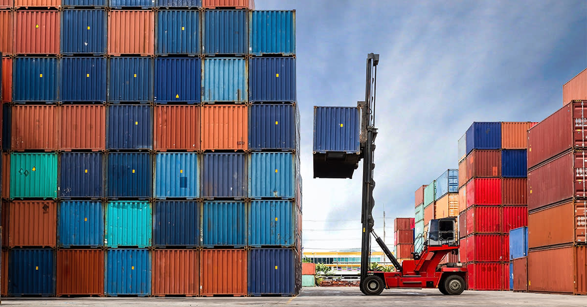 forklift surrounded by orange and blue shipping containers