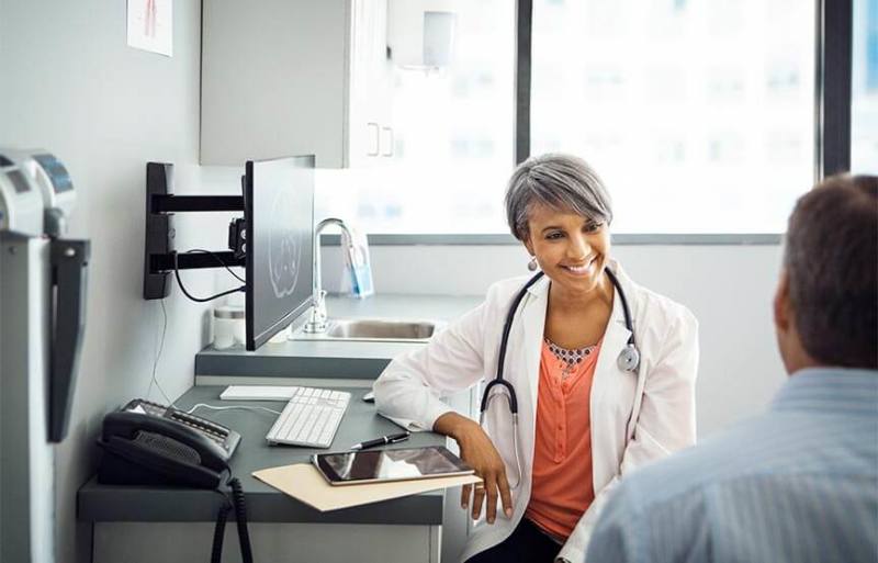 female doctor in white coat talking with patient in office