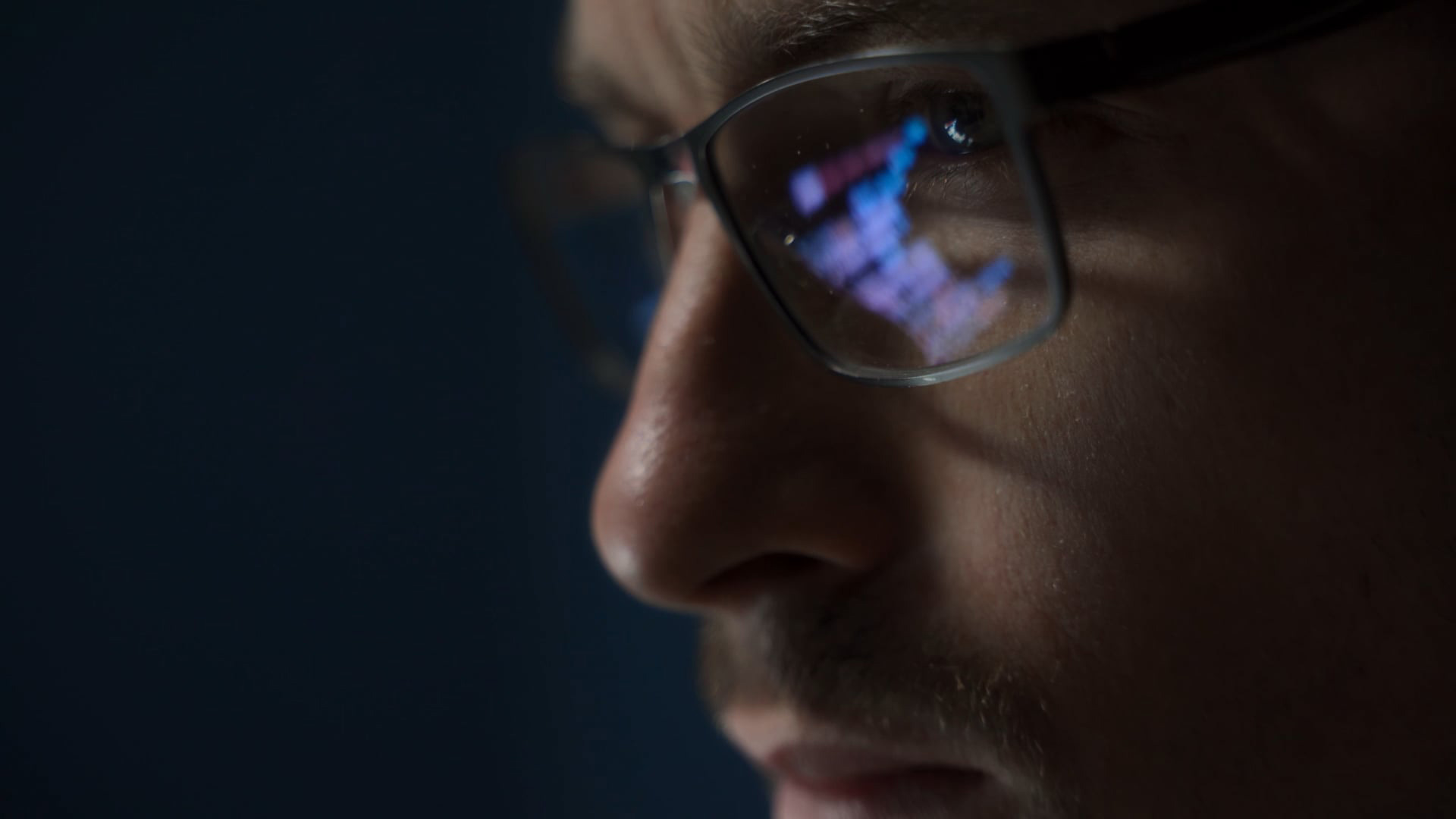 person looking at screen with computer reflecting in glasses 