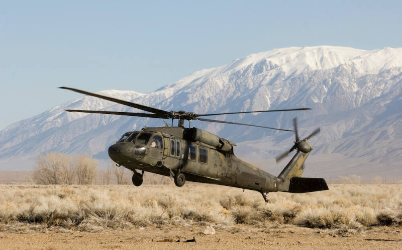 Military helicopter near ground with mountains in the background