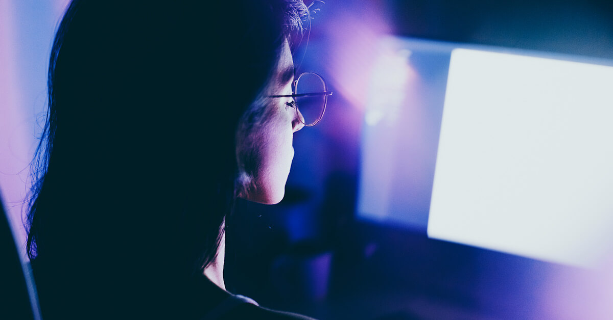 young woman working late on computer in a dimly lit room