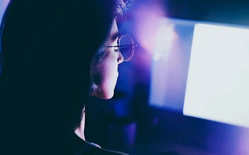 young woman working late on computer in a dimly lit room