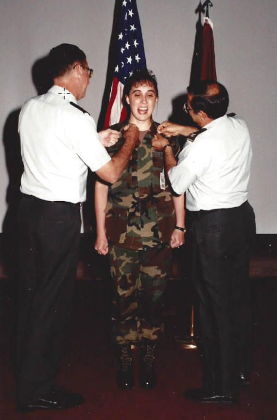 Solider standing with two people giving a medal to them