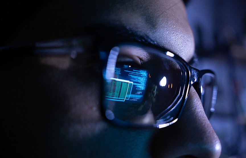 man wearing glasses who is working on computer, which is reflected in glasses lenses