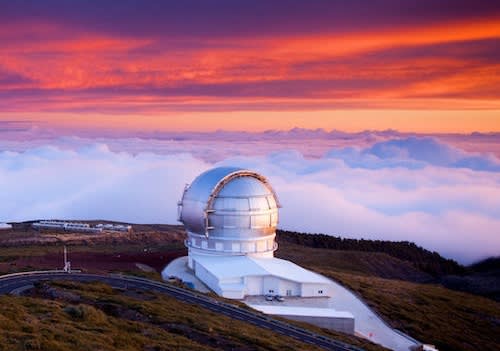 A space observatory with clouds in the background and a purple orange sky.