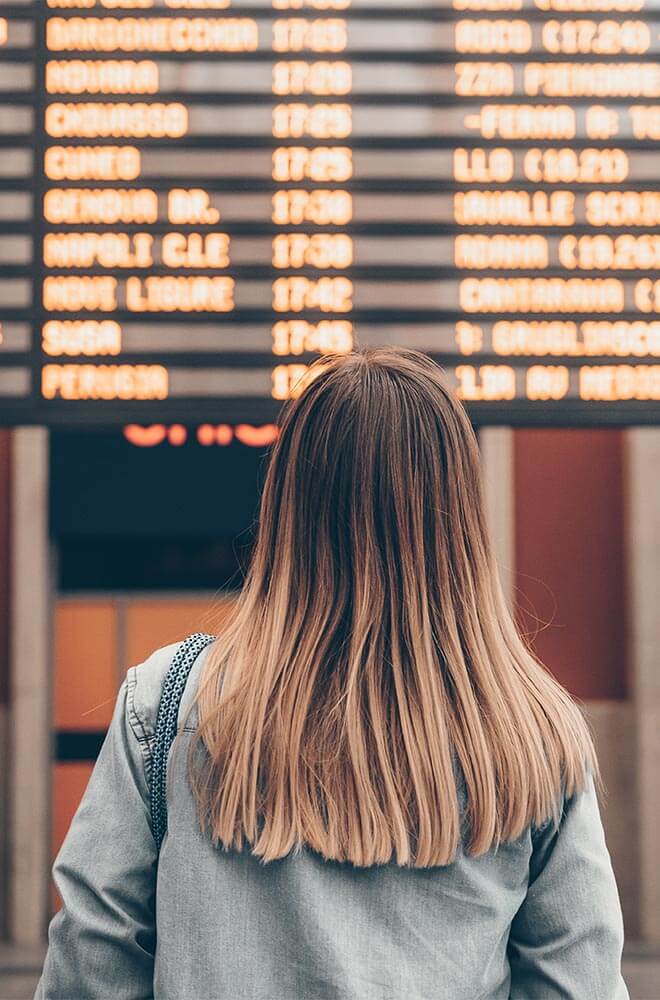 woman standing by departure board reading the times