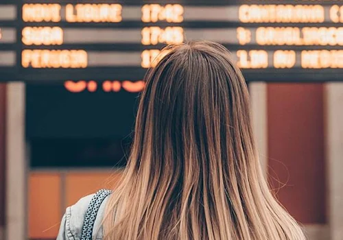 woman standing by departure board reading the times