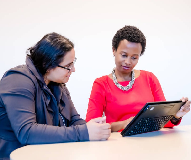 two people sitting together looking a laptop