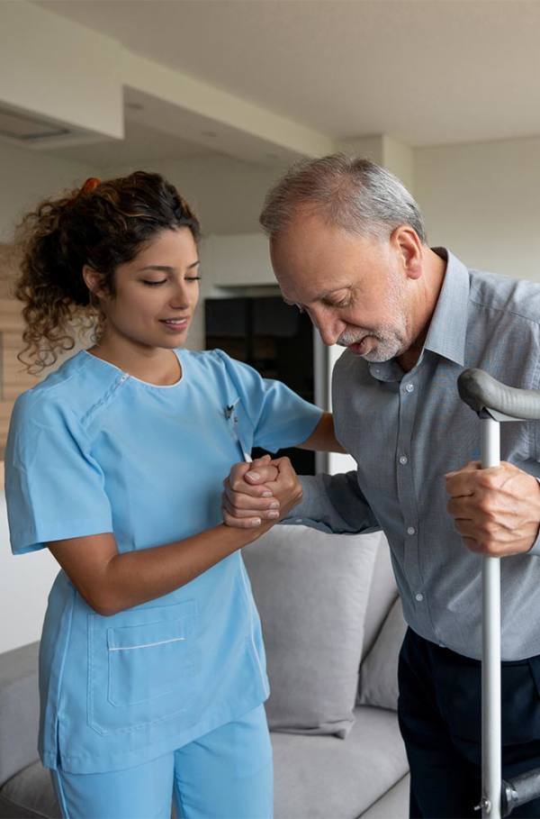 image shows a nurse helping someone stand with crutches 