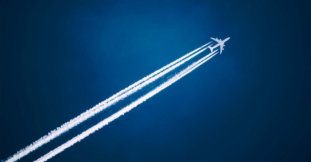 image shows airplane in sky with trail