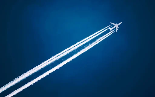 image shows airplane in sky with trail