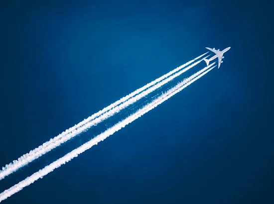image shows airplane in sky with trail